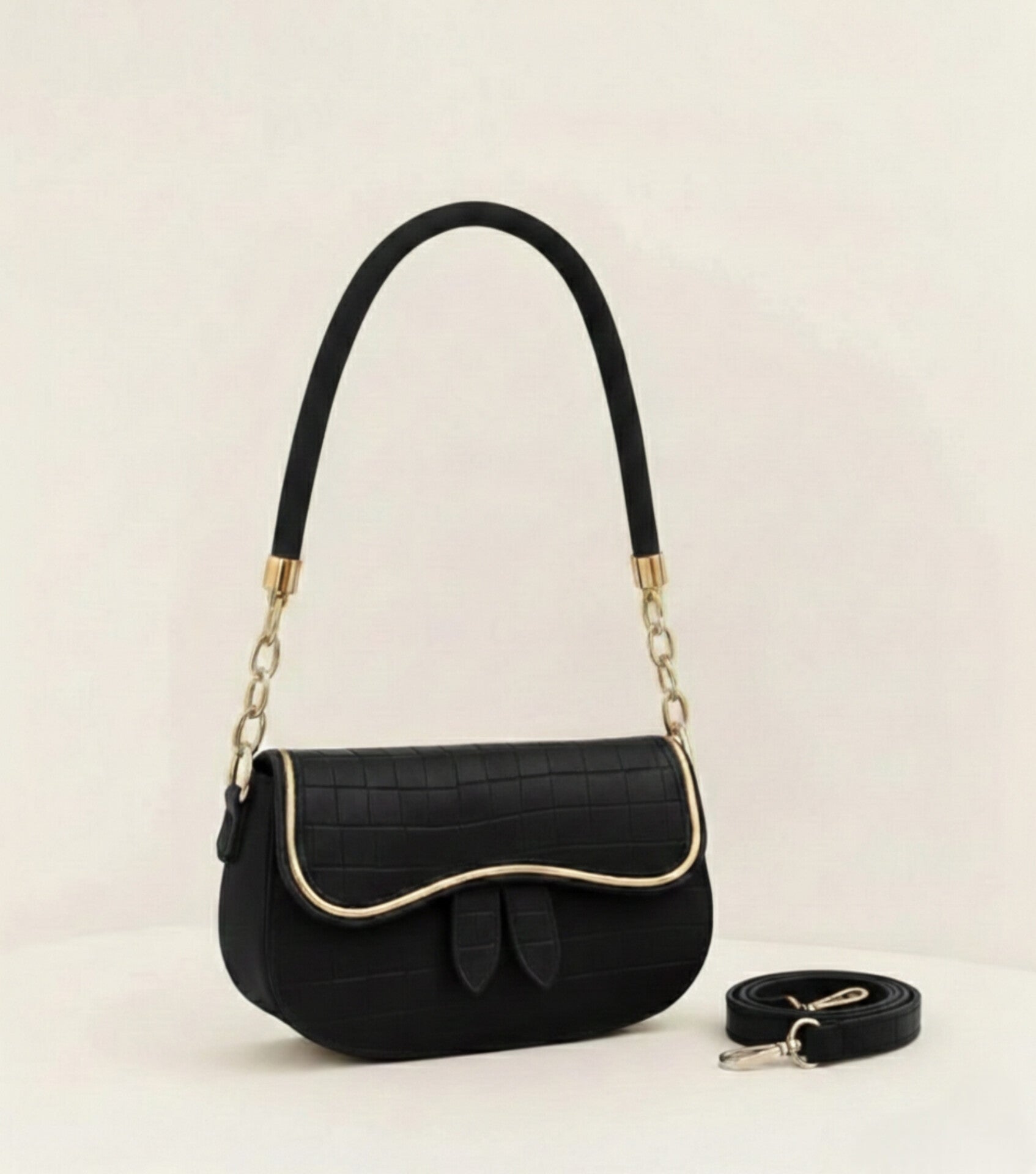 Black handbag with gold accents on a light beige background